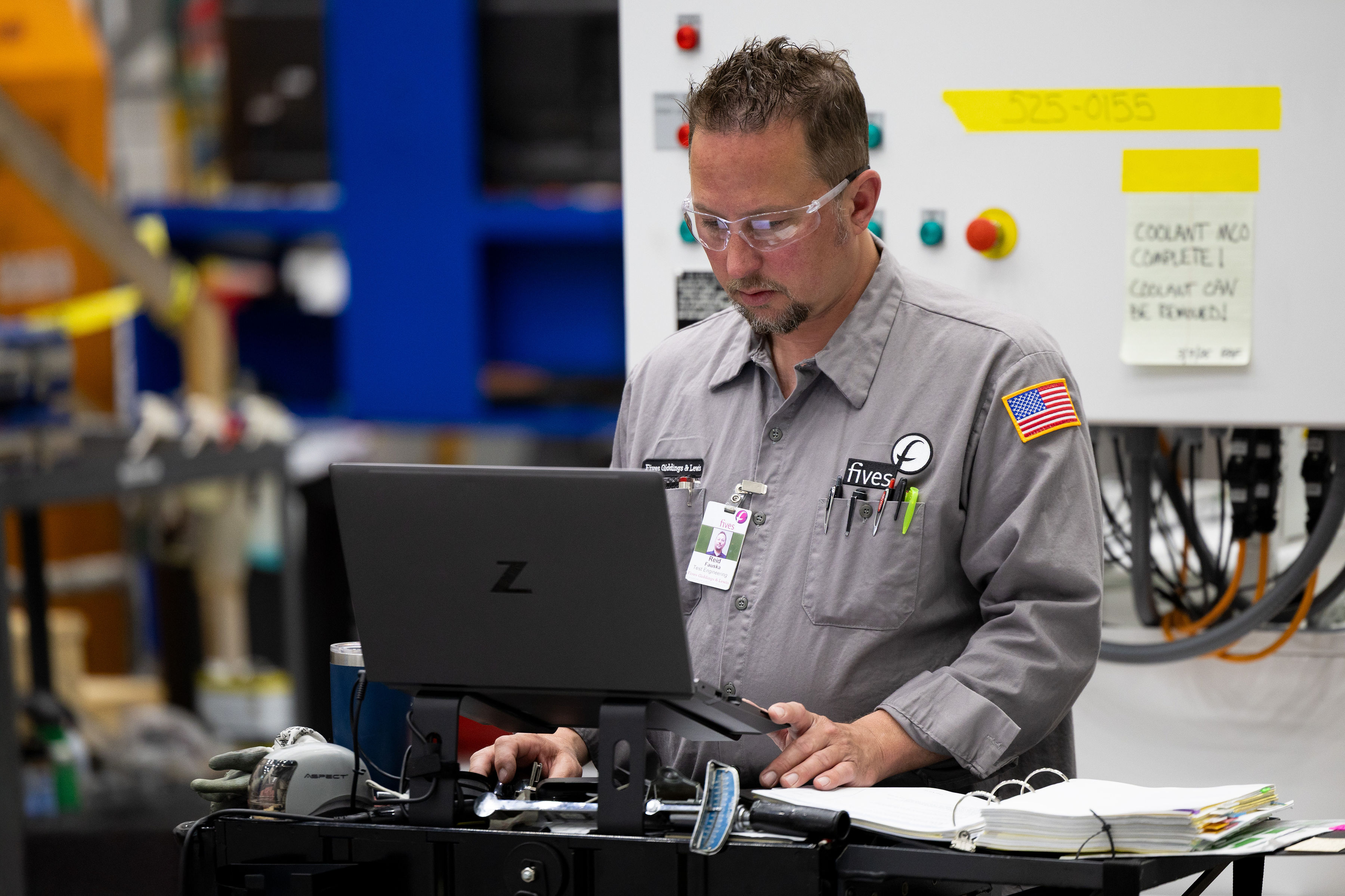 Fives maintenance specialist diagnosing industrial production equipment with a laptop
