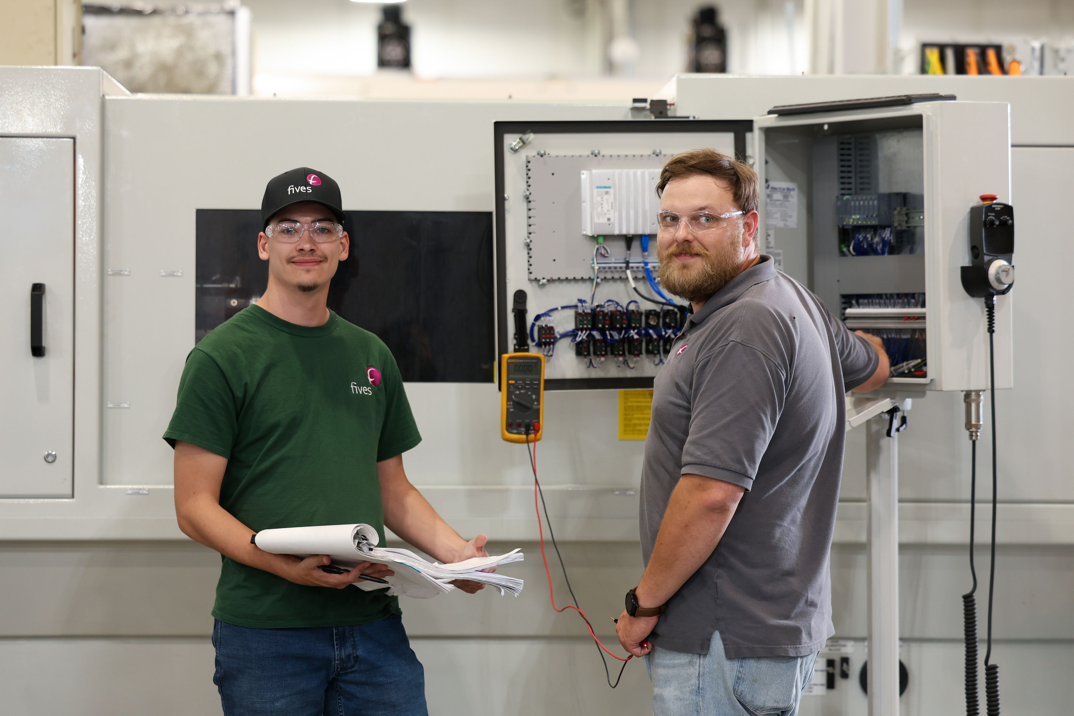Fives technicians reviewing industrial equipment controls and technical documentation