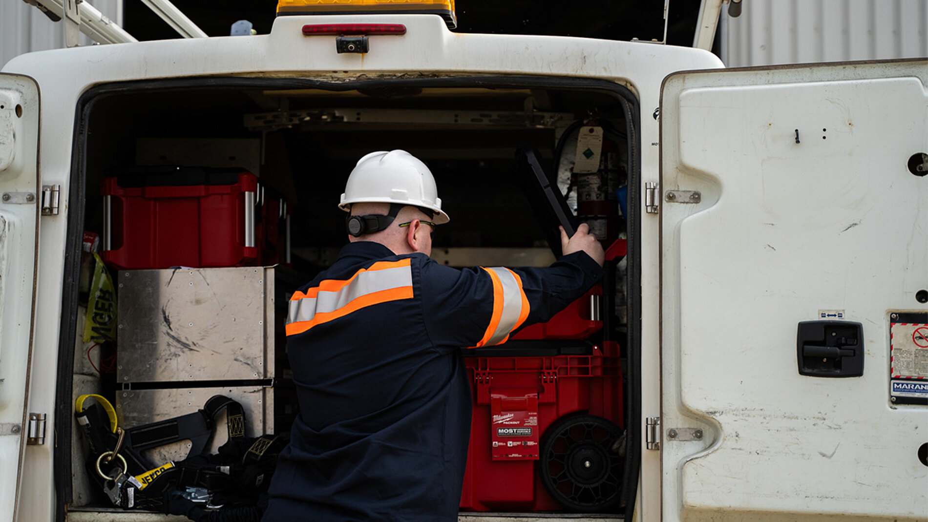 Employé organisant des outils et des équipements à l’intérieur d’un véhicule de service de l’entreprise