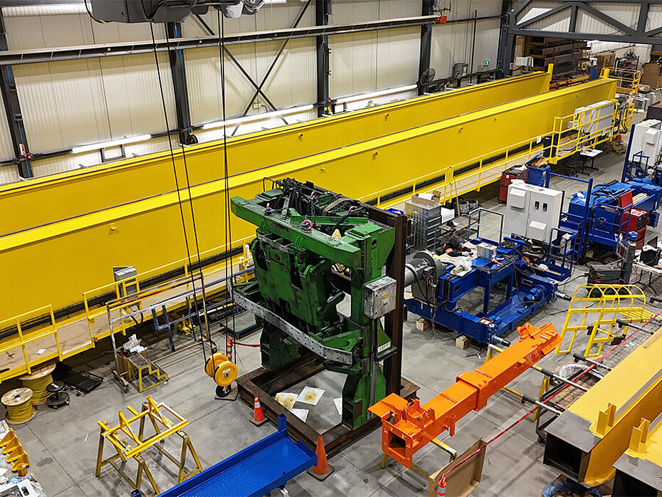 Vue en hauteur d’équipements de fabrication industrielle et de poutres de pont roulant jaunes à l’intérieur d’une grande usine de production.